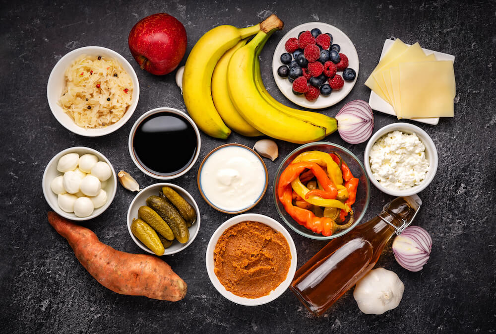 Alimenti probiotici e prebiotici, tra cui sottaceti, verdure, verdure fermentate, frutta e prodotti lattiero-caseari, ottimi per l'immunità e l'intestino.